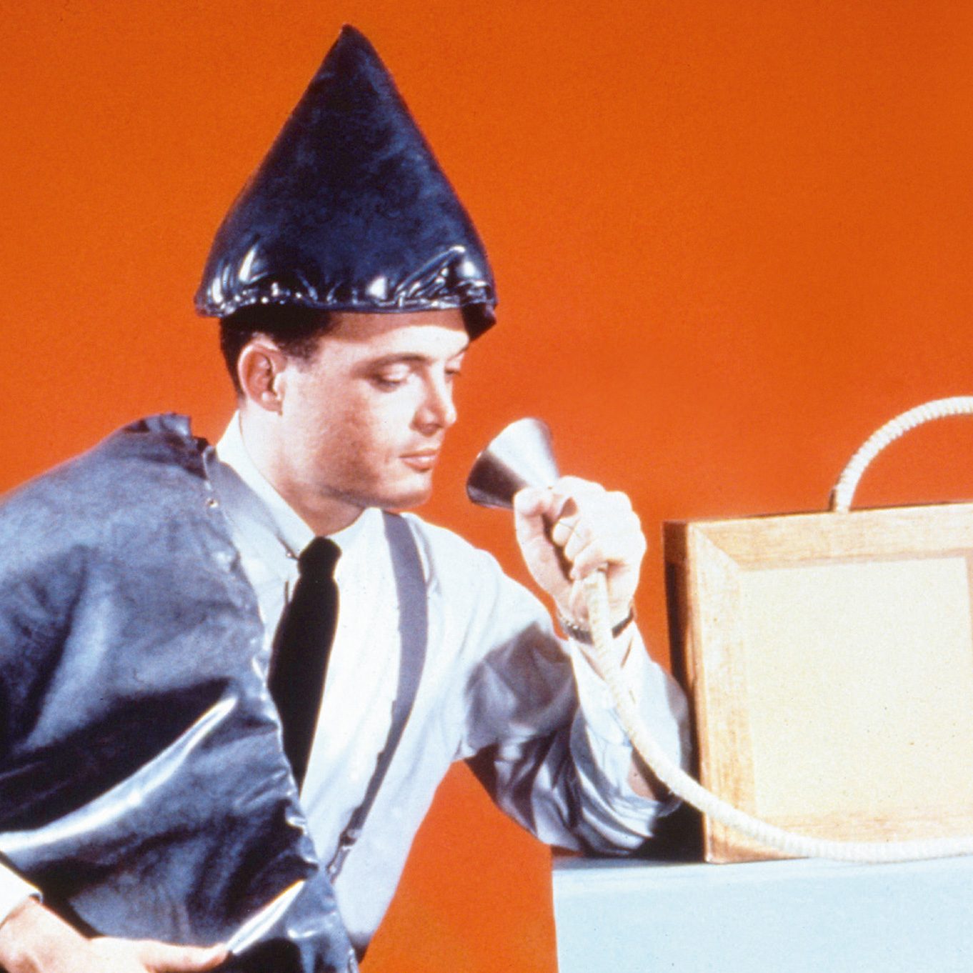 Orgone accumulator cabinet being used by a man in a pointed hat